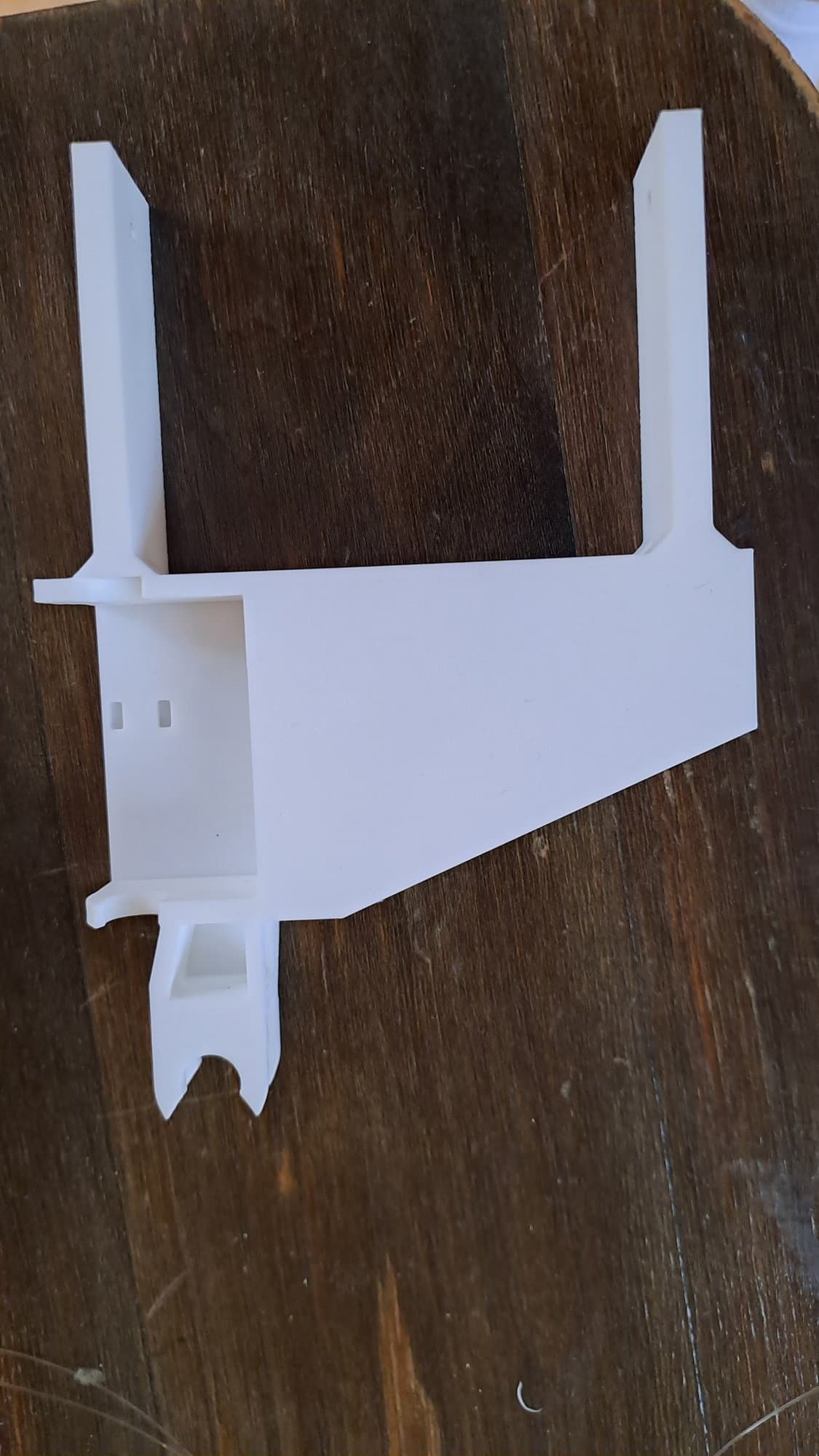 The white 3D-printed palm frame of the V0 prototype on a wooden table.