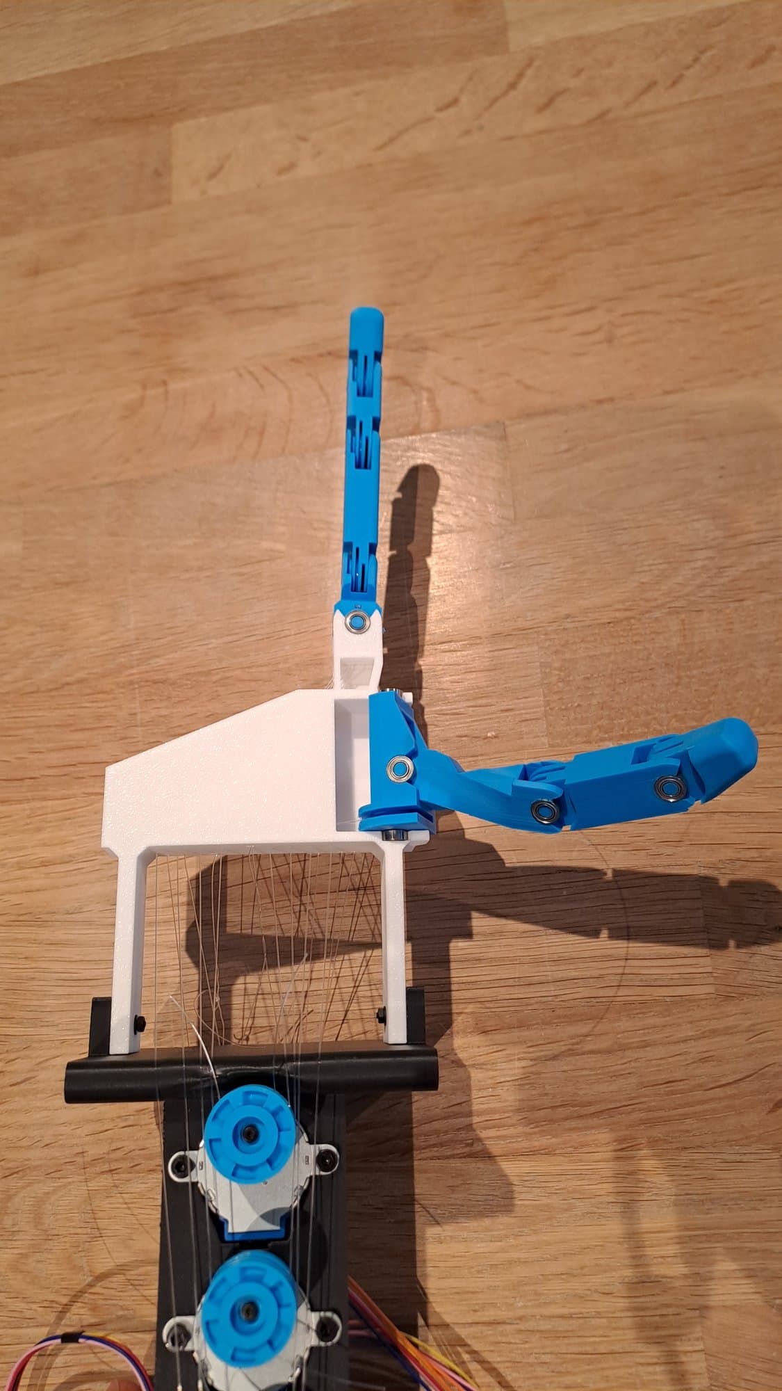 The thumb and index finger prototype seen from above, with the motor column and tendon spools below the palm.